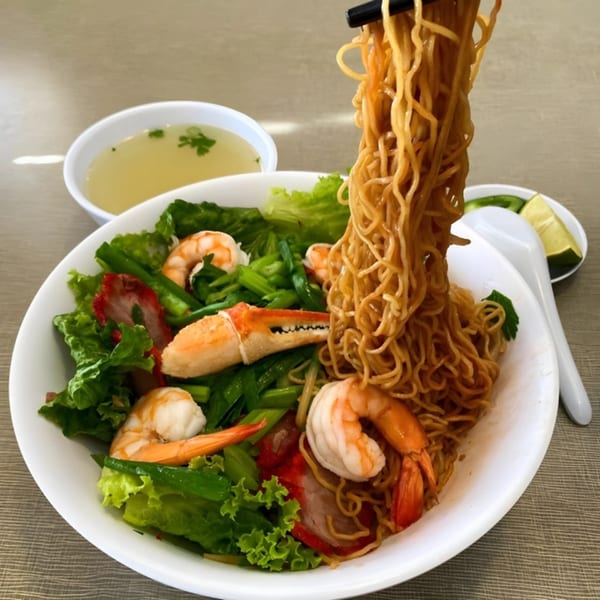 Chopsticks lifting Golden Deli's Vietnamese egg noodles with shrimp, crab claw, pork, and greens.