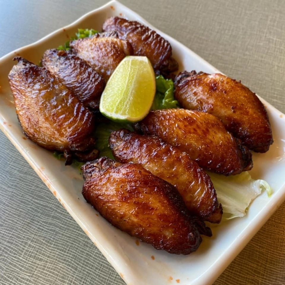 Golden Deli's Vietnamese chicken wings, glazed and golden brown, served with a lime wedge on lettuce.